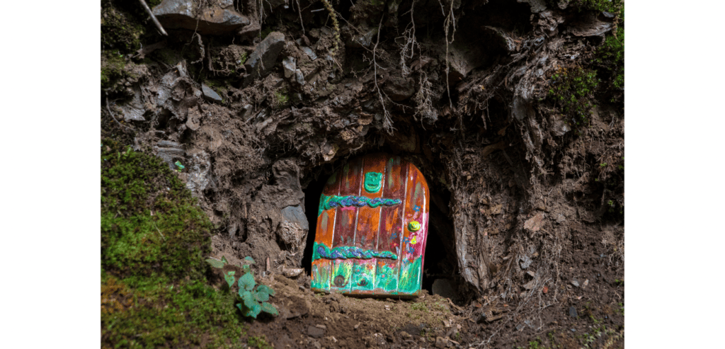 Small painted fairy door at foot of a tree