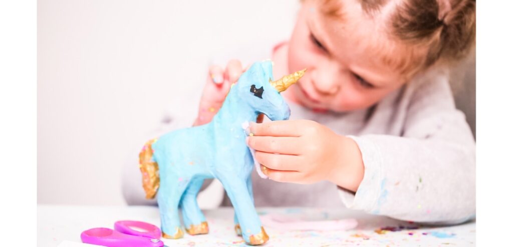 Little girl painting a model unicorn