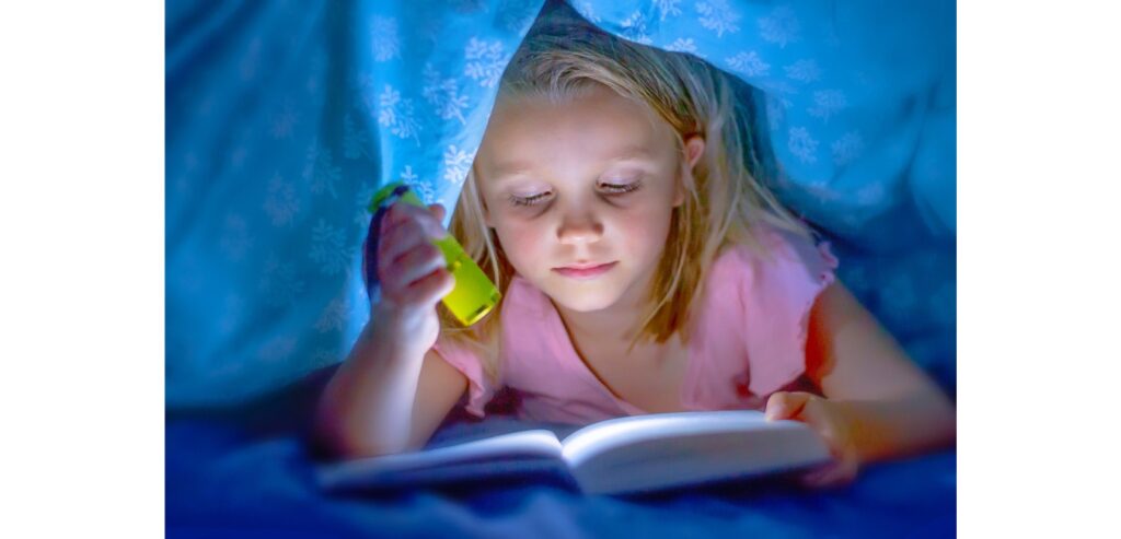 A girl reading her book by torch light