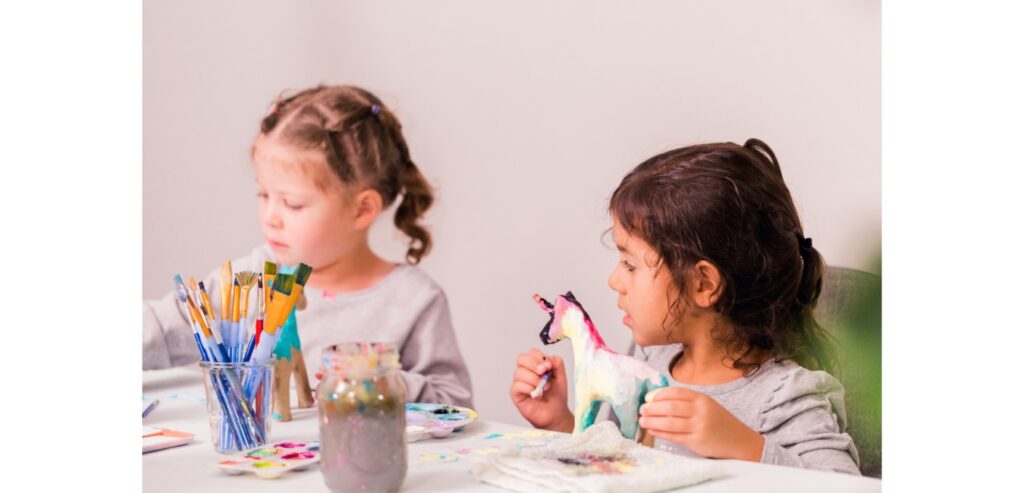 Two girls painting model unicorns