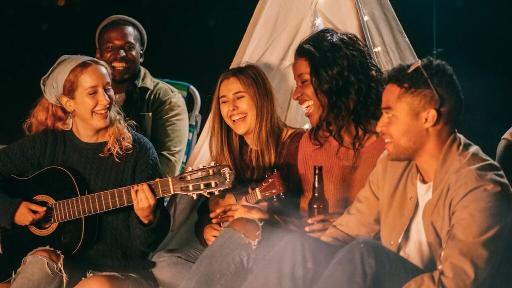Young people outside a tent with guitar