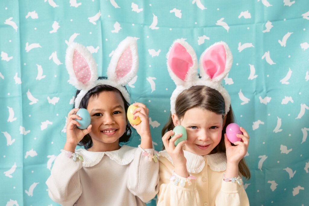 Two girls with bunny ears holding easter eggs - Easter celebrations and traditions for kids