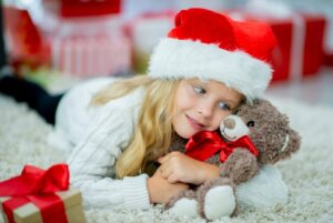 Little girl in Santa hat cuddling her teddy bear