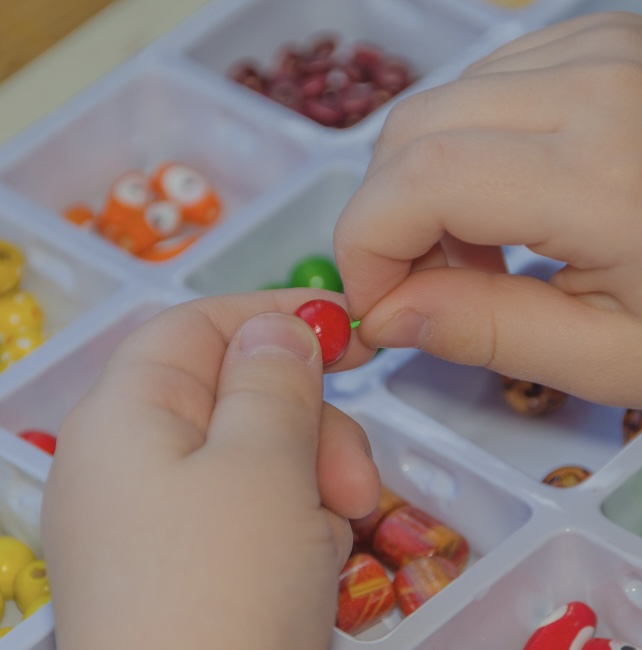 Child threading beads to make jewellery