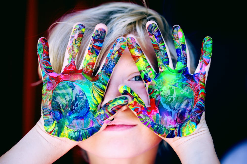 A child with hands covered in paints