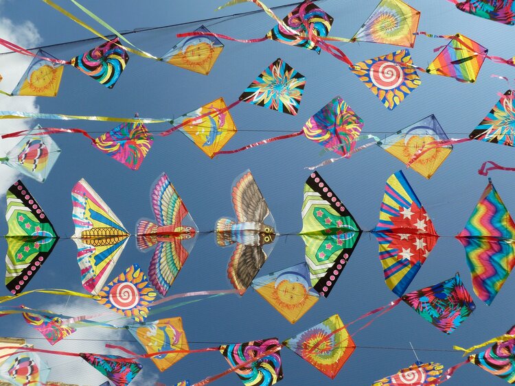 A large collection of coloured kites flying in the sky