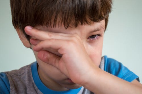 Boy crying and wiping his eyes